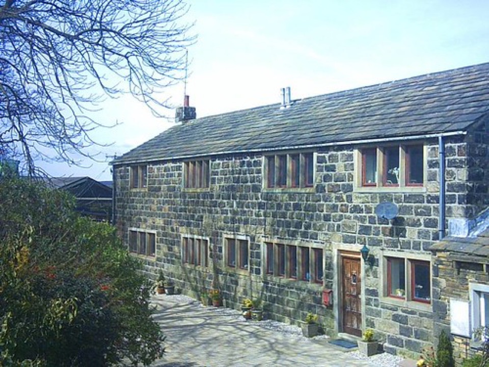 A long stone built house under a grey slate roof in West Yorkshire